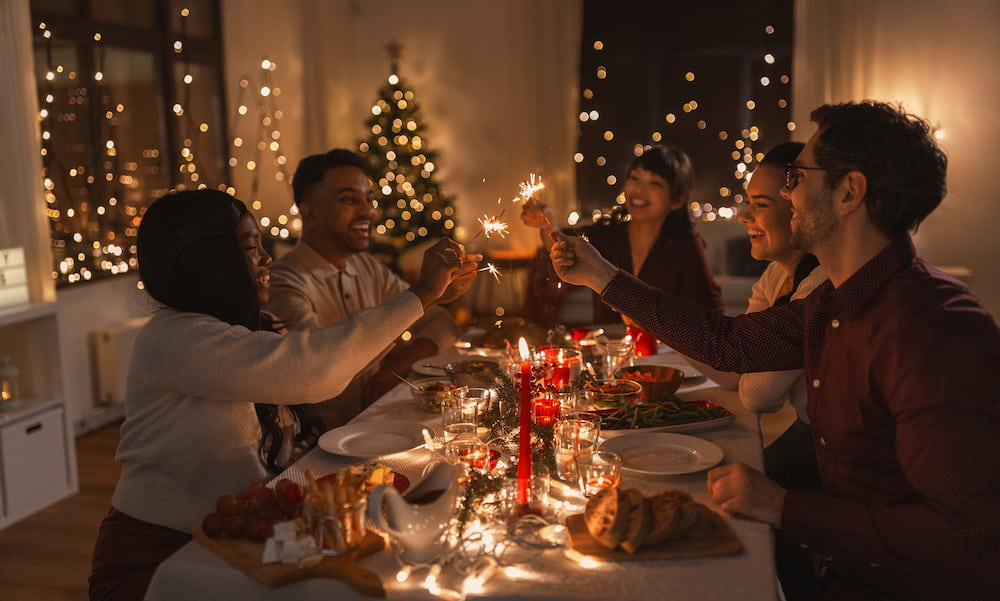 Friends sitting around a festive table with sparklers while hosting a holiday party